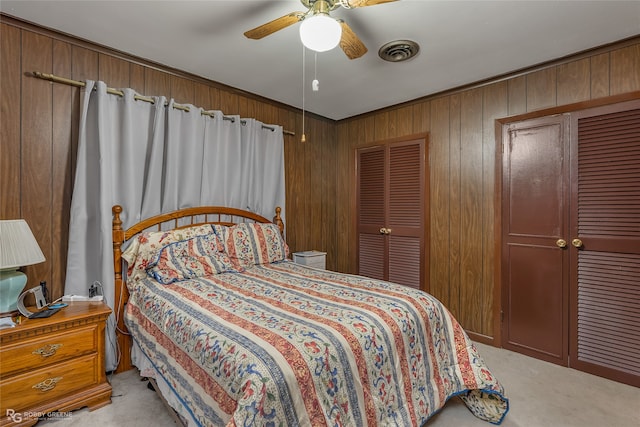 carpeted bedroom with ceiling fan, crown molding, and wooden walls