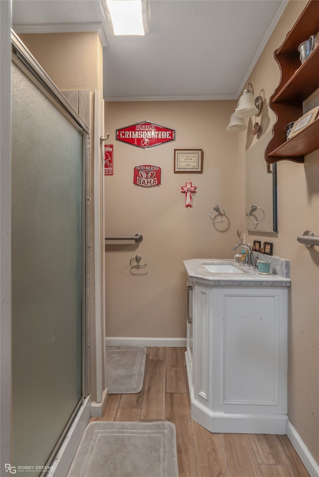 bathroom with hardwood / wood-style floors, vanity, a shower with door, and crown molding