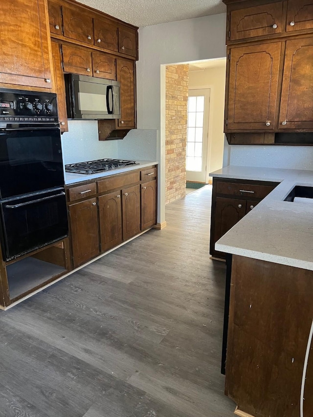 kitchen with dark hardwood / wood-style flooring, white gas cooktop, black double oven, and a textured ceiling