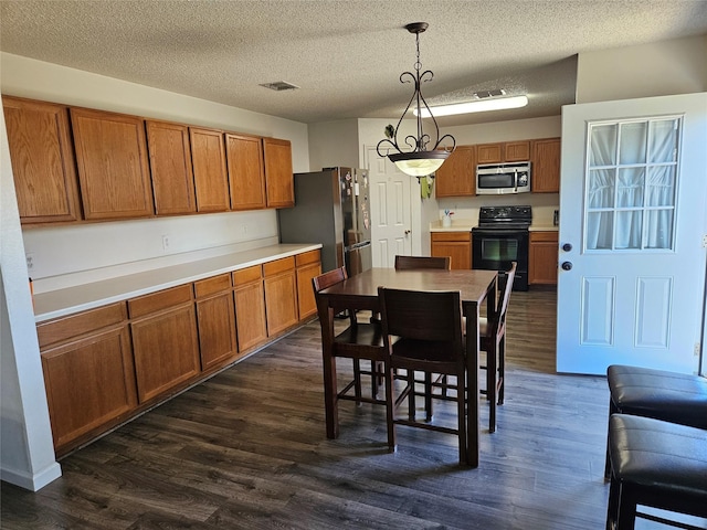 interior space with dark hardwood / wood-style flooring, hanging light fixtures, stainless steel appliances, and a textured ceiling