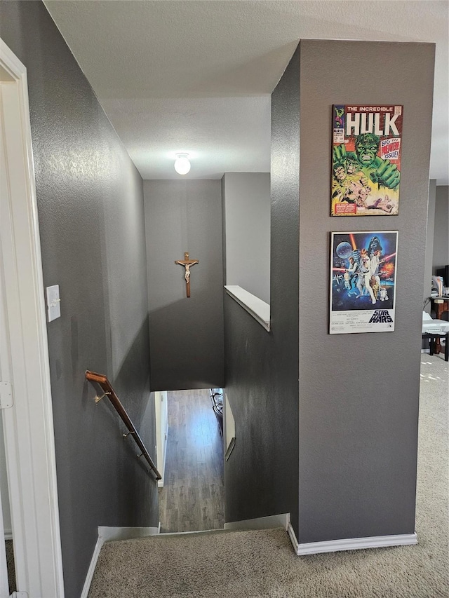 stairs featuring carpet flooring and a textured ceiling