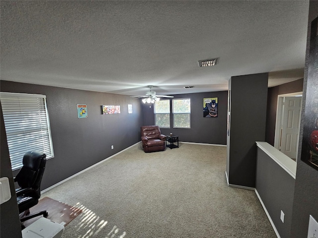 unfurnished office with light carpet, ceiling fan, and a textured ceiling