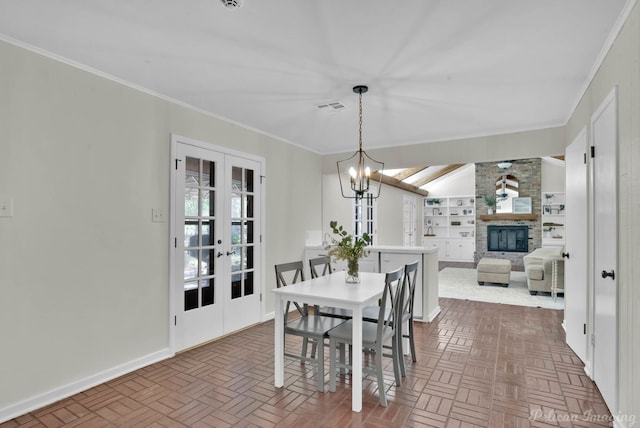 dining space with built in shelves, crown molding, a fireplace, and french doors