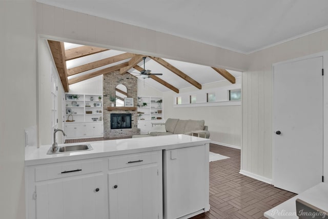 kitchen with lofted ceiling with skylight, sink, ceiling fan, built in features, and white cabinetry