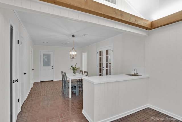 kitchen featuring kitchen peninsula, french doors, sink, an inviting chandelier, and hanging light fixtures