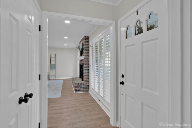 foyer entrance featuring a fireplace, light wood-type flooring, and crown molding