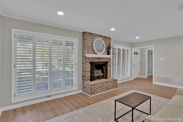 living room featuring wood-type flooring, crown molding, and a brick fireplace