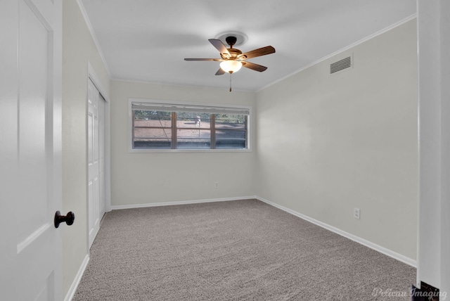 carpeted spare room featuring ceiling fan and crown molding