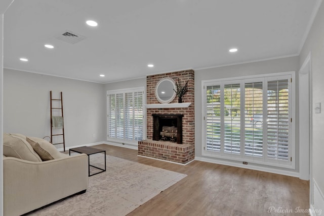 living room with a fireplace, light hardwood / wood-style flooring, a wealth of natural light, and ornamental molding