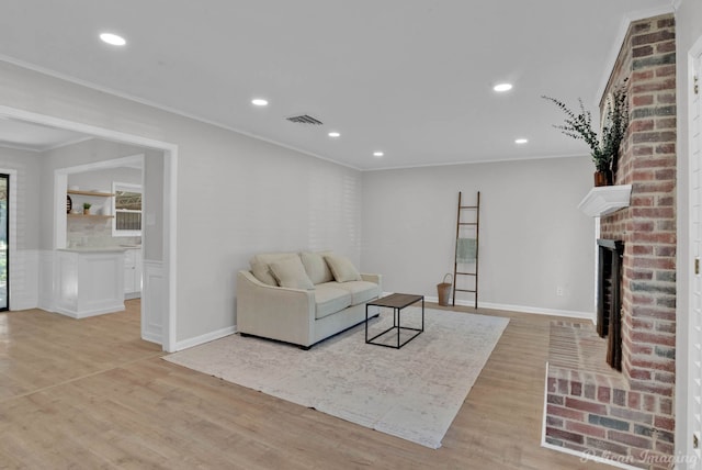 living room featuring a brick fireplace, light hardwood / wood-style flooring, and crown molding