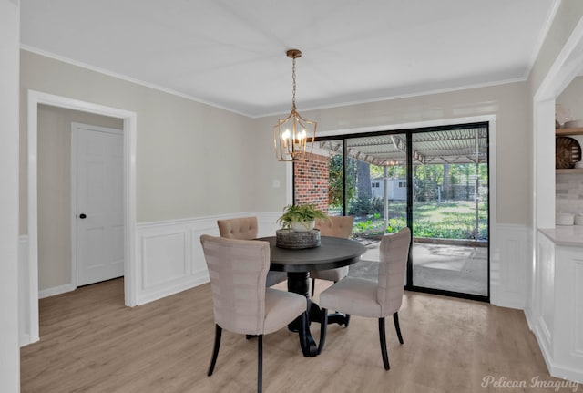 dining area featuring light hardwood / wood-style floors, ornamental molding, and an inviting chandelier