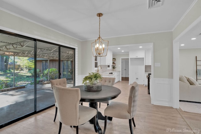 dining space featuring a chandelier, sink, light hardwood / wood-style floors, and ornamental molding