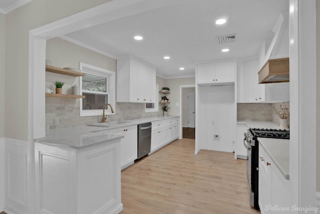 kitchen with custom range hood, stainless steel appliances, sink, light hardwood / wood-style flooring, and white cabinets