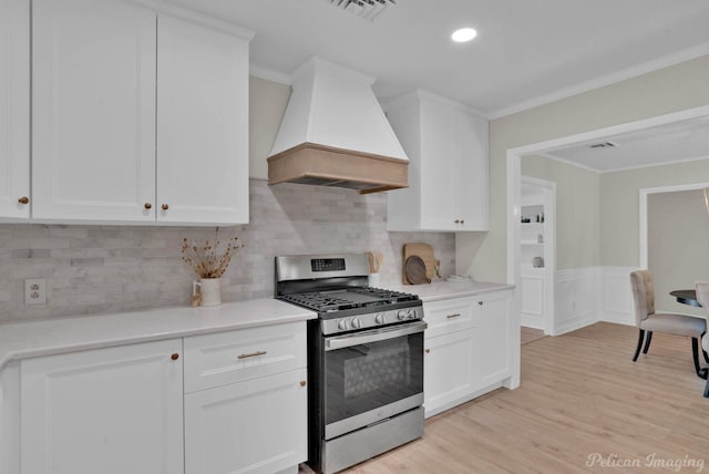 kitchen featuring white cabinets, gas range, premium range hood, and light hardwood / wood-style flooring