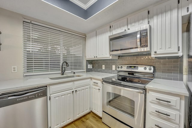 kitchen featuring sink, crown molding, stainless steel appliances, light hardwood / wood-style floors, and white cabinets