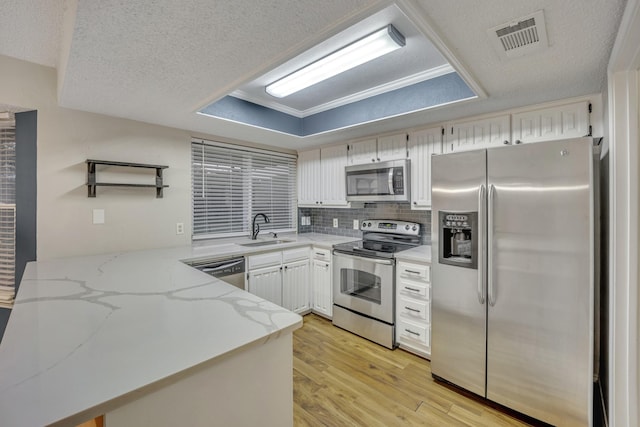 kitchen featuring light stone countertops, a textured ceiling, appliances with stainless steel finishes, white cabinetry, and sink