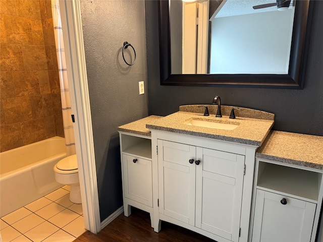 full bathroom with tiled shower / bath combo, vanity, ceiling fan, toilet, and tile patterned floors