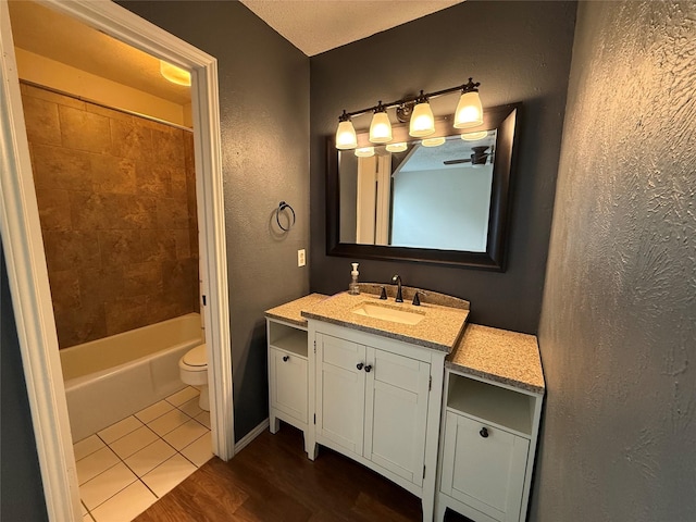 full bathroom featuring hardwood / wood-style flooring, vanity, tiled shower / bath, and toilet