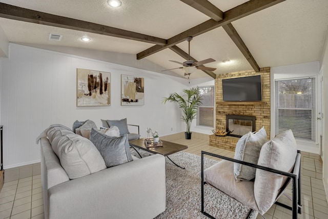 tiled living room with a brick fireplace, lofted ceiling with beams, a textured ceiling, and ceiling fan