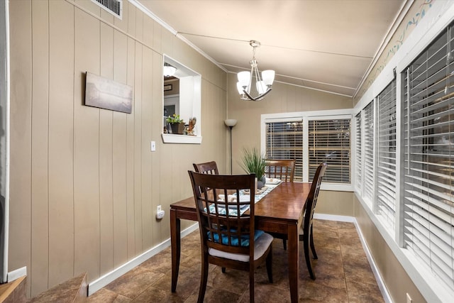 dining area featuring crown molding, lofted ceiling, an inviting chandelier, and wood walls