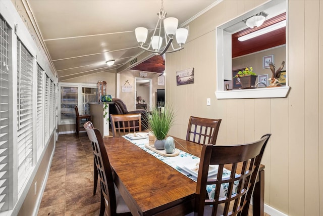 dining area featuring ornamental molding, a chandelier, vaulted ceiling, and wood walls