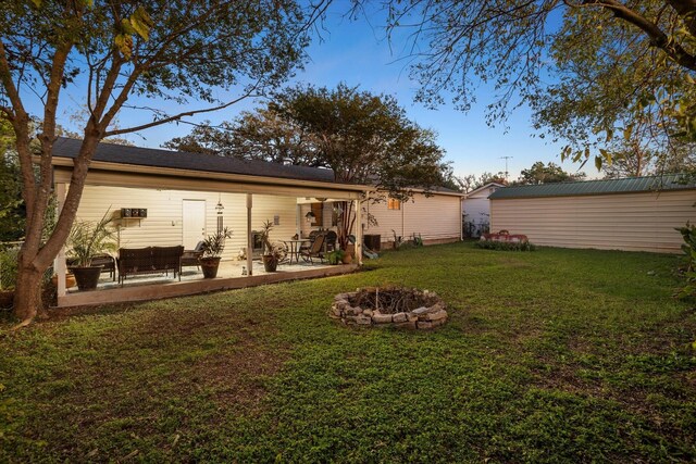 back of house featuring a yard, a patio area, and an outdoor fire pit