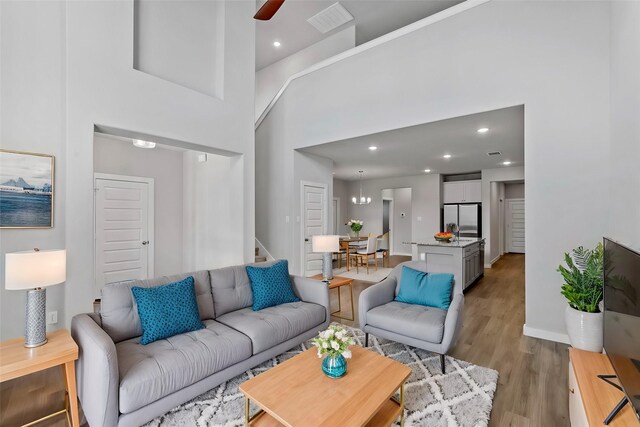 living room with a high ceiling, light wood-type flooring, and ceiling fan