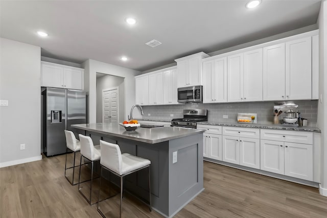 kitchen with white cabinets, appliances with stainless steel finishes, and a kitchen island with sink