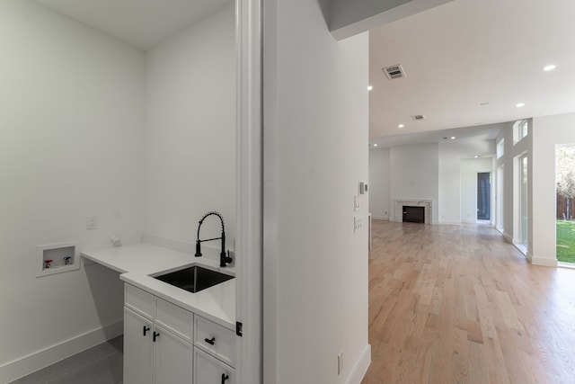 laundry area with cabinets, hookup for a washing machine, light wood-type flooring, and sink