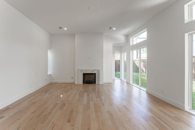 unfurnished living room with light hardwood / wood-style floors and a high ceiling