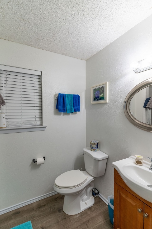 bathroom with a textured ceiling, vanity, hardwood / wood-style flooring, and toilet