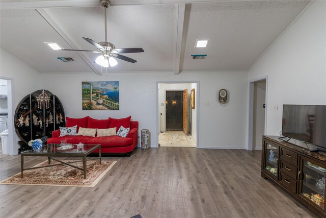 living room with vaulted ceiling with beams, ceiling fan, light hardwood / wood-style floors, and a textured ceiling