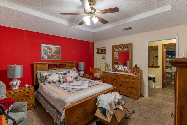 bedroom featuring carpet flooring, a raised ceiling, ceiling fan, and a textured ceiling