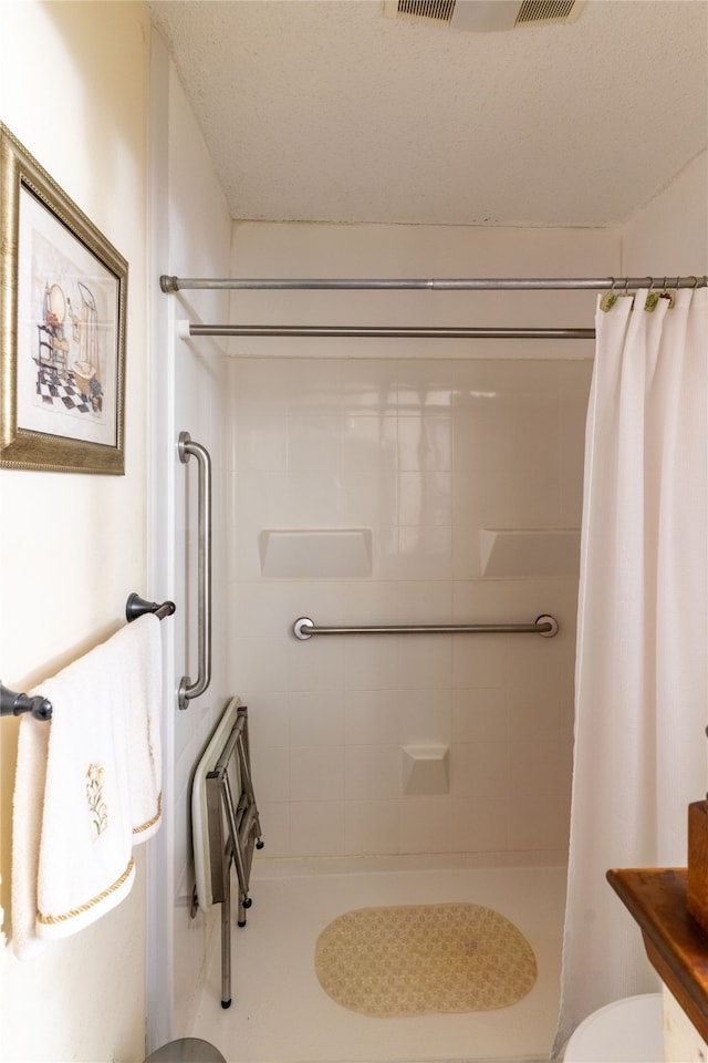 bathroom with a shower with curtain, toilet, and a textured ceiling