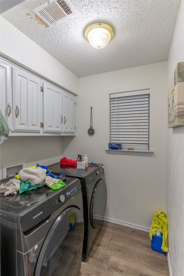 washroom with cabinets, hardwood / wood-style floors, a textured ceiling, and independent washer and dryer