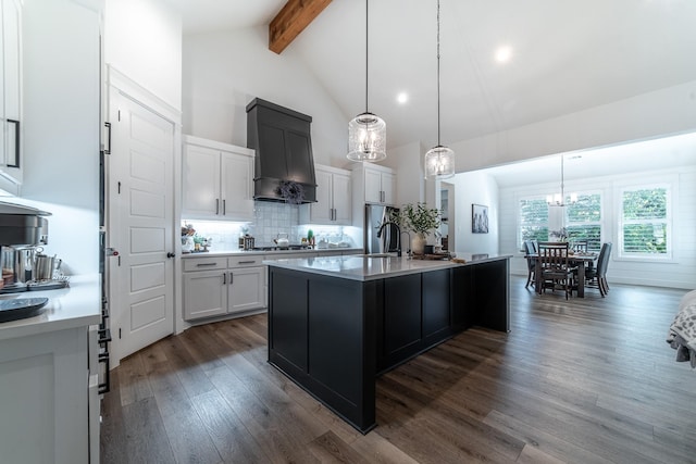 kitchen with beam ceiling, dark hardwood / wood-style flooring, an island with sink, decorative light fixtures, and white cabinets