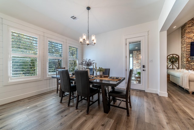 dining area with wood-type flooring and an inviting chandelier