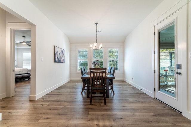 dining area with ceiling fan with notable chandelier and dark hardwood / wood-style floors