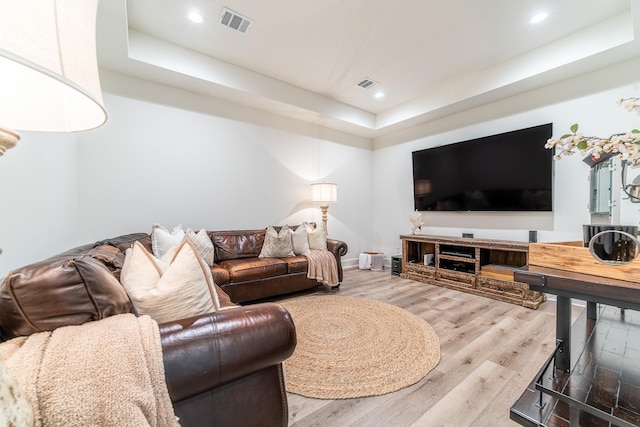 living room with hardwood / wood-style flooring and a tray ceiling