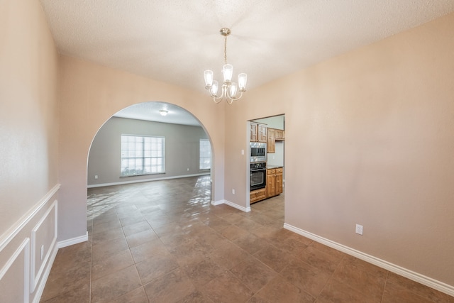 unfurnished dining area with a textured ceiling and an inviting chandelier