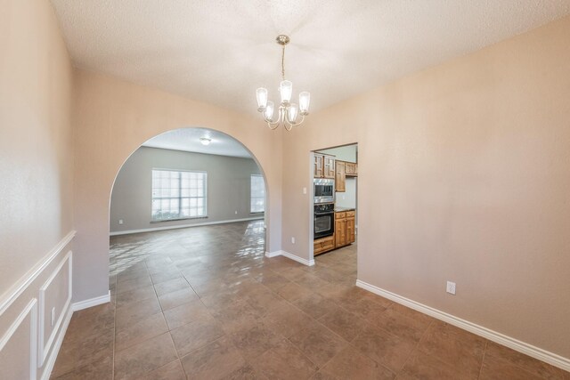 unfurnished dining area with a textured ceiling and an inviting chandelier