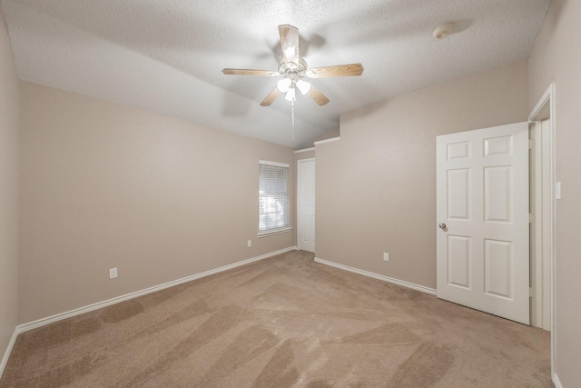 empty room featuring a textured ceiling, light colored carpet, and ceiling fan