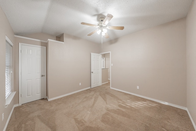 unfurnished bedroom featuring a textured ceiling, ceiling fan, light colored carpet, and lofted ceiling