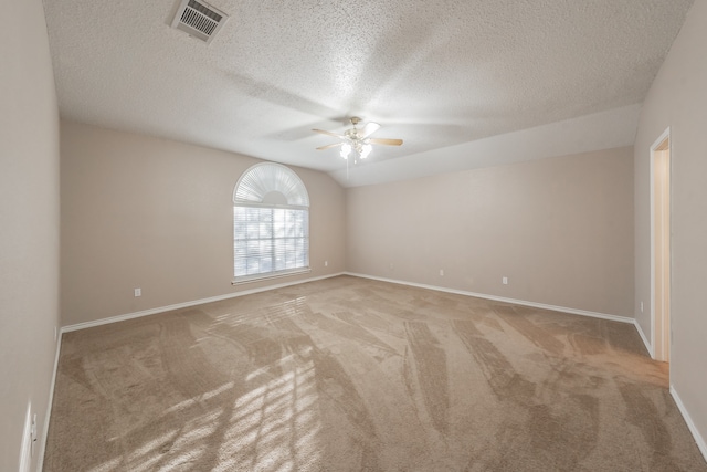 carpeted spare room featuring a textured ceiling, vaulted ceiling, and ceiling fan