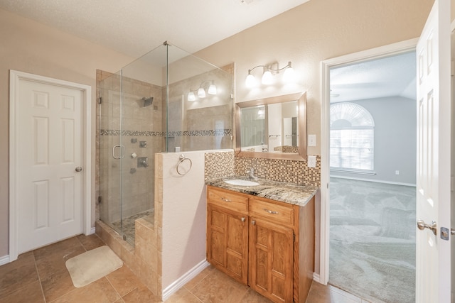 bathroom featuring backsplash, vanity, an enclosed shower, and vaulted ceiling