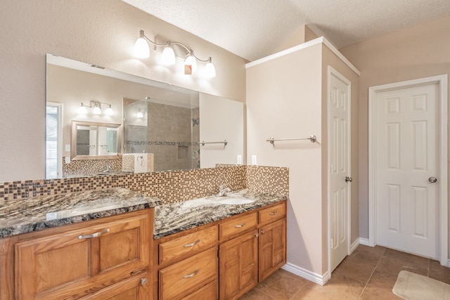 bathroom featuring backsplash, tile patterned floors, a textured ceiling, vanity, and tiled shower