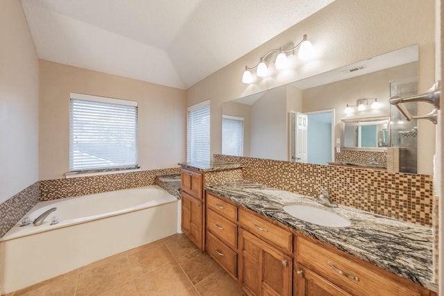 bathroom featuring tile patterned floors, vanity, a tub, and lofted ceiling