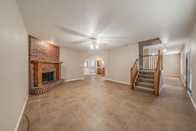 unfurnished living room with ceiling fan, a fireplace, and a textured ceiling