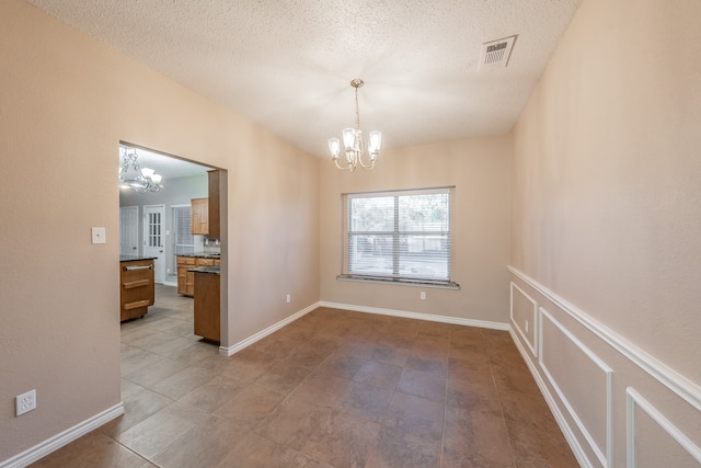 unfurnished dining area featuring tile patterned floors, a notable chandelier, and a textured ceiling