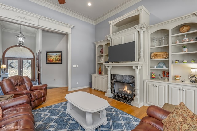 living room featuring hardwood / wood-style floors, a high end fireplace, french doors, and ornamental molding